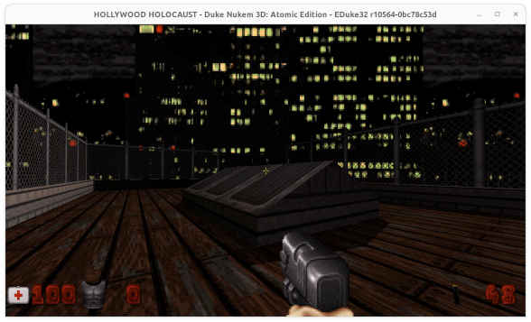 Captura de pantalla de Duke Nukem 3D. Se ve una mano con una pistola en la azotea de un edificio